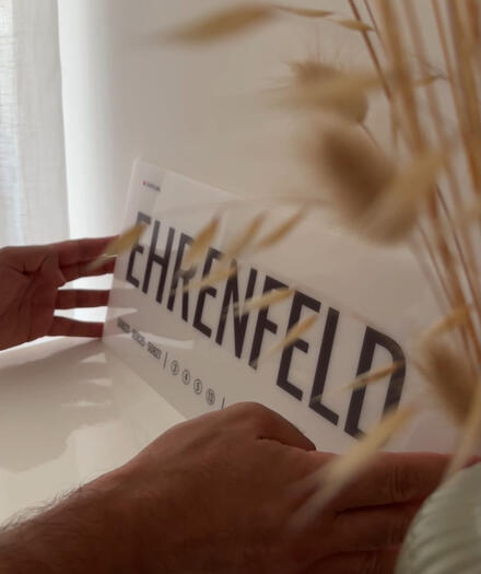 Leicht und hochwertig verarbeitet. Das Acrylglas-Designschild „Ehrenfeld“ von DasIstColonia wird in den Händen gehalten und zeigt seine hochwertige Verarbeitung. Design Straßenschild für Köln-Liebhaber